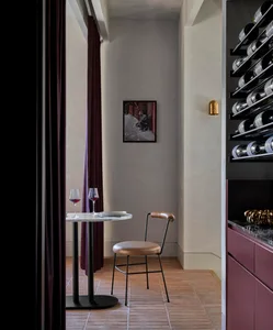 A modern wine bar with metal and leather furniture, featuring a round table with wine glasses and a chair.