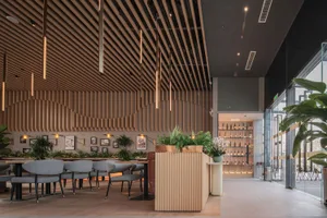 Modern interior of a cafe-bar with wooden slat walls, glass elements, and plants