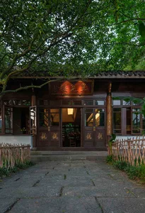 A traditional Chinese house with wooden exterior and tile roof, surrounded by lush greenery.