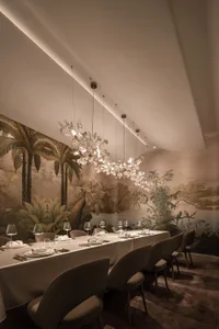 An elegant restaurant dining room with a jungle-themed mural, plush seating, and elaborate lighting fixtures.