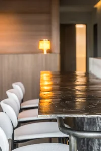 A sleek, modern restaurant interior featuring a metal and marble bar counter illuminated by warm, ambient lighting.