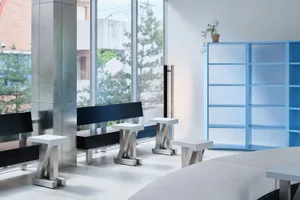 A modern minimalist library with clear glass furniture, white walls, and large windows.