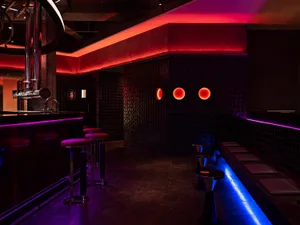 Bar with industrial design featuring metal stools, concrete flooring, and glass elements.