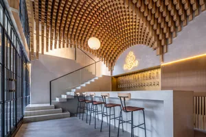 Modern restaurant interior with wooden ceiling, seating area, and signage.