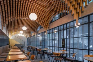 Contemporary wooden restaurant interior with hanging lamps and large windows.