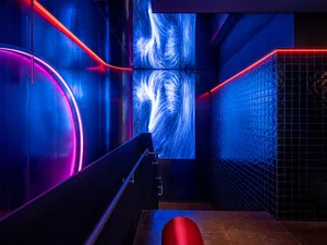 A modern nightclub interior featuring vibrant blue lighting and contemporary concrete elements.
