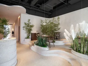 A minimalist restaurant interior with concrete walls and wavy planters