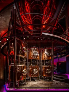Large metallic vats in a circular room with red lighting and modern design elements.