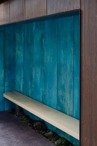 A minimalist interior design featuring a wooden bench and blue wooden walls.