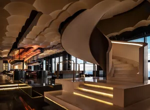 Modern industrial-style bar and spiral staircase with metal railings and concrete steps and floor.