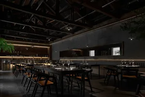 A dark, industrial-style restaurant with black steel chairs, concrete flooring, and wooden elements.