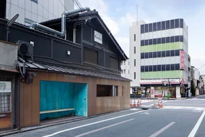 A street view image featuring a traditional Japanese building with a concrete facade.