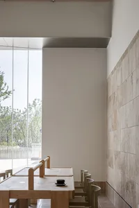 A minimalist cafe featuring wooden tables and stone walls.