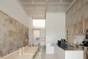 Modern cafeteria with wooden tables, tiled walls, and glass display case.