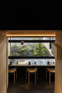 Modern restaurant interior featuring minimalist design with concrete, wood, and stone materials.