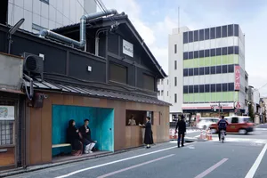 人們坐在傳統日式建築外，街道背景有現代建築。