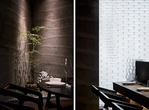 A serene restaurant interior featuring a textured concrete wall and minimalist dining setup.