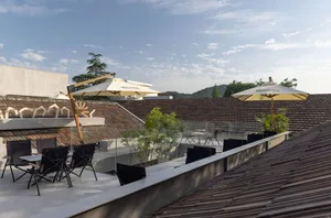 Outdoor rooftop terrace with tiles, pine trees, and dining tables.