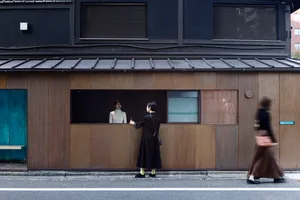 A person standing outside a small building with a metal exterior.