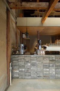 A coffee shop interior with a concrete and wooden counter.