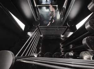 A modern, black metal staircase with a polished stone floor.