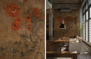A modern restaurant interior featuring a wall art with floating orange circles and wooden furniture.