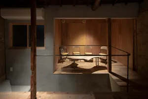 Minimalist room with wooden walls and floor, featuring a wooden table and chairs