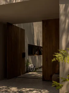 A modern residential entrance featuring wooden doors and concrete flooring.