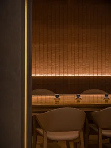 現代餐廳室內，暖色燈光、棕色布料與木質家具。