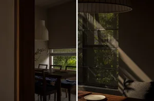 A modern dining room with a wooden table, chairs, and a large window with blinds.