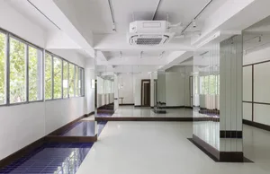 A minimalist dance studio with white flooring and mirrored glass walls.