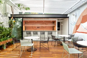 A modern cafe bar with metallic furniture, featuring a sleek, minimalist design with a bar counter and seating areas.