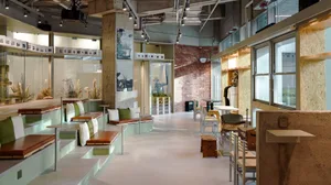 A modern cafe with exposed brick walls and concrete floor, featuring seating areas and tables.