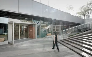 A modern coffee shop storefront with a glass facade and a man walking past.
