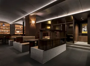 A modern restaurant interior with wooden seating, concrete walls, and illuminated shelves.