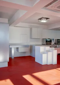 A modern kitchen interior with white cabinets and red flooring.
