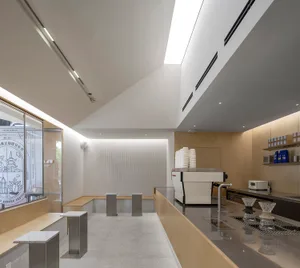 A minimalistic coffee shop interior predominantly made of white concrete materials, featuring sleek lines and modern design e