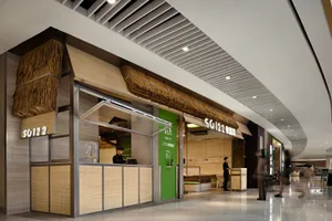 A minimalist restaurant interior featuring bamboo elements and green accents.