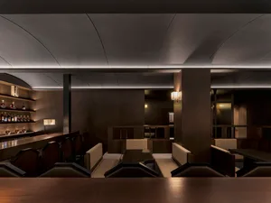 A modern restaurant bar with dark wood and high gloss surfaces.