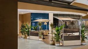 A modern retail cafe with wooden and glass features, adorned with plants.