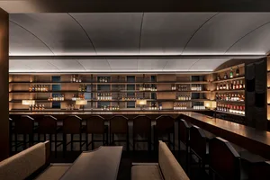 A modern restaurant bar showcasing wooden interiors and a wide selection of liquor bottles.