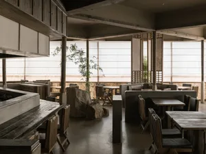 A modern restaurant with wooden tables, stone accents, and large windows