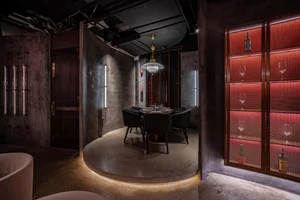 A modern restaurant interior featuring concrete flooring, glass walls, and metal accents.