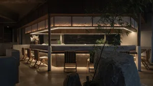 Modern minimalist restaurant interior featuring concrete, stone, and wood with warm lighting.