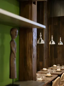 A modern industrial restaurant interior with wooden furniture and metallic pendant lights.
