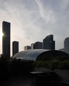 A glass-covered building stands prominently against a cityscape backdrop.