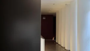 View of a hotel corridor featuring white cylindrical columns and black walls.