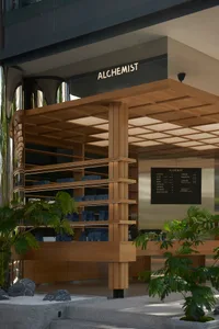 Modern coffee shop with wooden shelves filled with coffee bags, green plants, and a menu board displaying the coffee options.