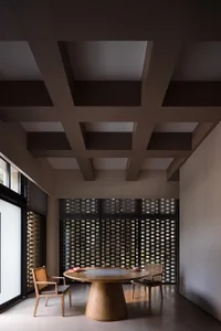 A modern residential dining room featuring a wooden table and chairs with a geometric patterned wall.