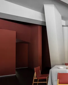 Restaurant interior with red walls, concrete flooring, and modern furniture.